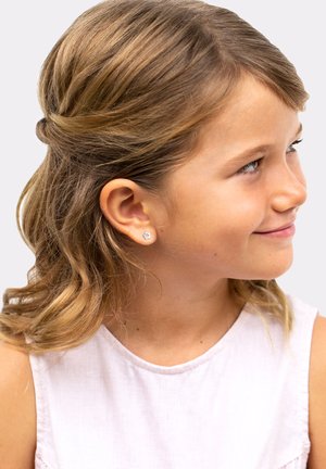 Piccole orecchini a perno in argento con un design floreale, caratterizzati da una gemma blu chiaro al centro, indossati da un bambino con capelli ondulati di colore marrone chiaro.