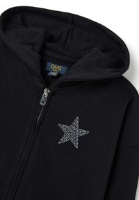 Sudadera negra con cremallera hecha de suave algodón, que presenta un diseño de estrella plateada en strass en el pecho y una capucha adjunta.