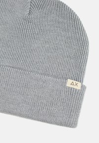 Beanie grigio lavorato a maglia con texture a coste e risvolto. Presenta un piccolo etichetta beige con un logo triangolare.