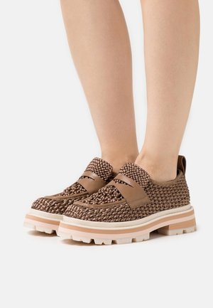 Chaussures en textile tissé marron avec une épaisse semelle extérieure blanche et rose. Présentent une lanière en cuir lisse sur le dessus et une languette à l'arrière.