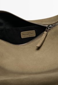 Brun ruskindsarmbåndtaske med lynlåslukning, der har et sort stofinteriør og et lædermærke, der står "Massimo Dutti" indeni.