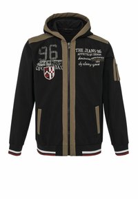 Zwarte capuchonjas met beige accenten, voorzien van ritssluiting, voorzakken en bedrukte afbeeldingen inclusief nummers en tekst.