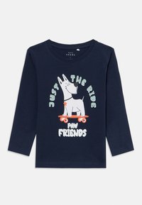 Navy long-sleeve shirt featuring a cartoon dog on a skateboard, with the text "Just the Ride" and "Paw Friends" in playful colors.