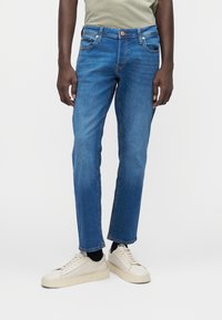 Τζιν παντελόνι σε ανοιχτό γαλάζιο χρώμα, με ίσια γραμμή, πέντε τσέπες, κούμπωμα με κουμπί και ελαφριά ξεθώριασμα. Συνδυασμένο με εκρού αθλητικά παπούτσια.