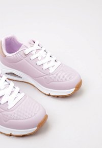 Sneaker rosa chiaro con lacci bianchi, texture perforata e suola intermedia bianca. Suola in gomma di colore beige, completata da un design elegante.