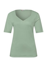 Chemise à manches courtes vert clair avec encolure en V et une petite étiquette de marque à l'intérieur du col.