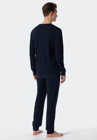 Marineblauwe katoenen loungekleding set met een langmouw t-shirt met ronde hals en bijpassende elastische broek met enkelboorden. Glad textuur, ontspannen pasvorm.