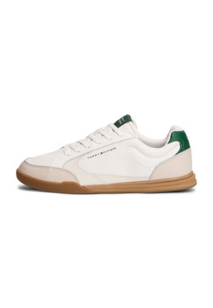 Biały niski sneaker z beżowym noskiem, zielonymi akcentami na pięcie i języku, beżową podeszwą i logo Tommy Hilfiger po boku.