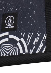 Tela negra y blanca de la marca Volcom con un diseño texturizado y estampado que presenta elementos circulares y a rayas, sobre un fondo oscuro.