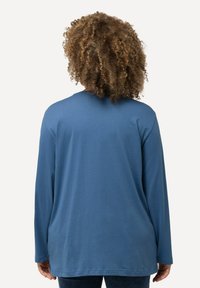 Langärmliges blaues Hemd aus weichem Stoff. Rundhalsausschnitt und lockere Passform, mit geradem Saum und minimalen Nähdetails.