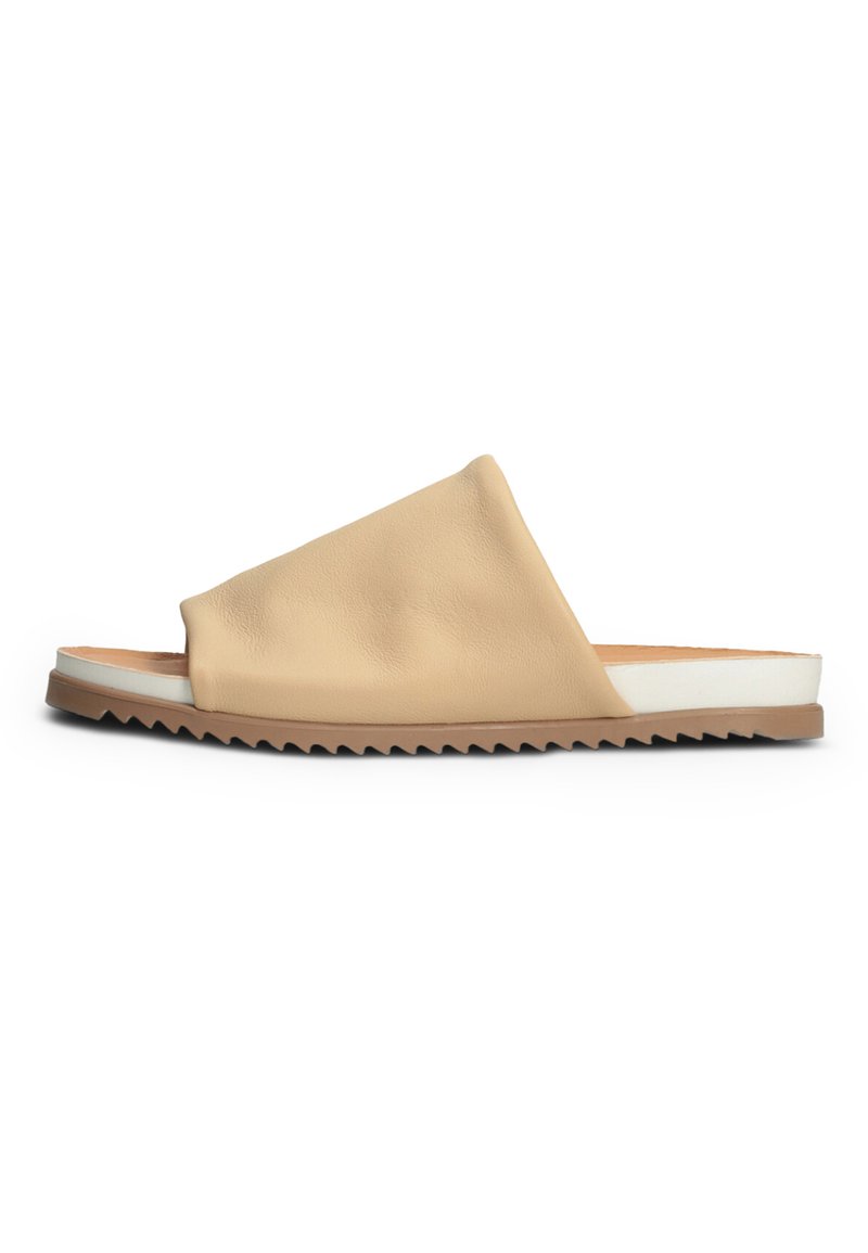 Beige leather slide sandal with an asymmetrical design, white midsole, and zigzag patterned outsole for added grip and style.