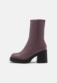 Bota de imitación de cuero morado hasta la mitad de la pantorrilla con puntera redondeada, caña elástica y tacón cuadrado negro alto. Textura suave, diseño minimalista.