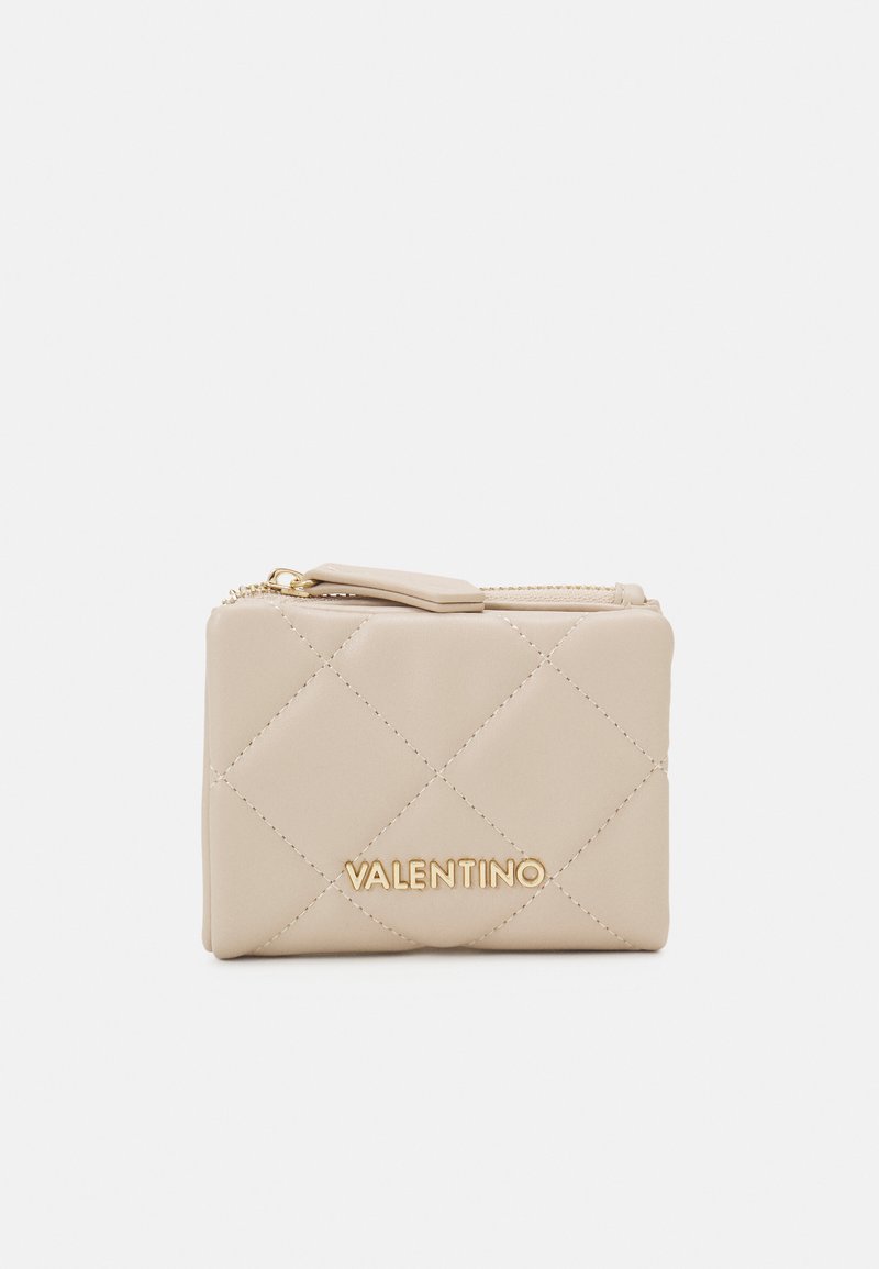 Bež novčanik od quilted kože s zlatnim hardverom i zatvaranjem na patentni zatvarač. Ima elegantan pravokutni oblik i utisnutu oznaku brenda sprijeda.