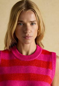 Ärmelloser Strickpullover mit breiten horizontalen Streifen in Rosa und Rot, einem gerippten Rundhalsausschnitt und einer weichen Textur.