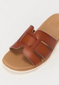 Brune skinn slide sandal med åpen tå-design, doble horisontale stropper og teksturert fotseng. Lett såle med svak heving.