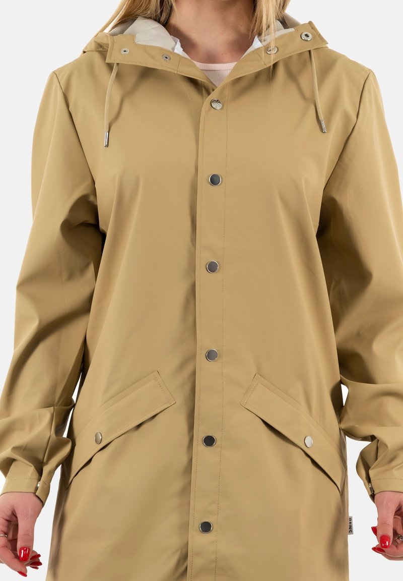 Imperméable beige clair avec capuche, boutons-pression, poches plates et finition texturée. Cordon de serrage ajustable au niveau du cou.