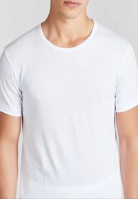 T-shirt bianca in cotone con collo tondo e maniche corte. Presenta una texture liscia e un taglio classico, adatto per l'abbigliamento casual.