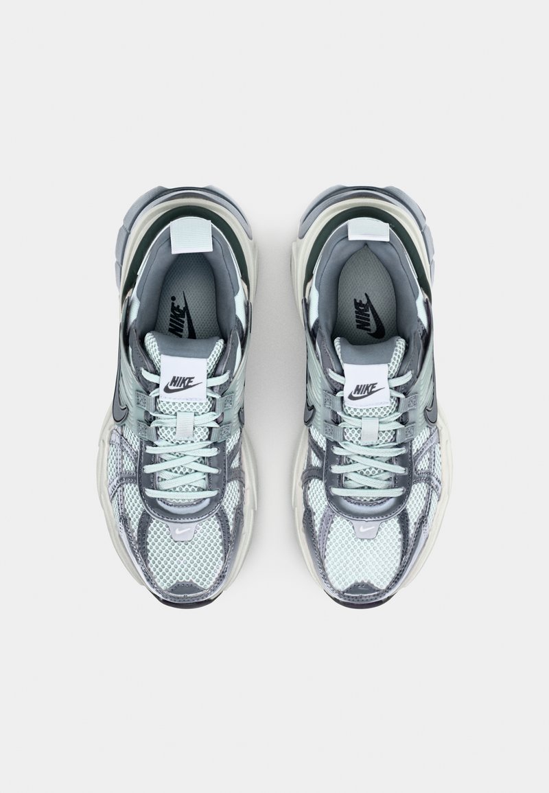 Zapatillas Nike gris y verde menta con materiales de malla y cuero, que cuentan con una lengüeta acolchada, diseño de cordones y suela texturizada.