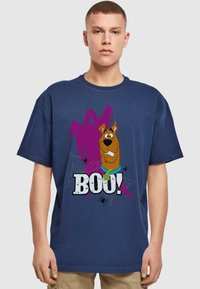 Navy blue cotton t-shirt featuring a cartoon dog next to a purple ghost. "BOO!" text in bold, with spider and web illustrations.