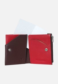 Portafoglio in pelle a due pieghe con sezioni marroni e rosse, tasca con zip, slot per schede e una scheda bianca parzialmente visibile.