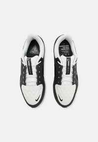 Schwarz-weiße Sneaker mit einer gequilteten weißen Zehenkappe, schwarzen Mesh-Seiten, flachen Schnürsenkeln und einem markanten Nike-Logo an der Außenseite.