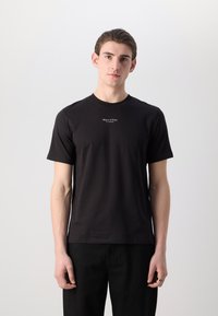 Tricou din bumbac negru, cu mâneci scurte, guler rotund și un mic text alb cu logo pe piept. Textură netedă cu o croială standard.