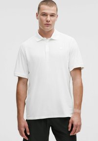 Biela polokošeľa s krátkymi rukávmi a jemnou ryhovanou textúrou. Obsahuje klasický golier a malú logo detail na hrudi.