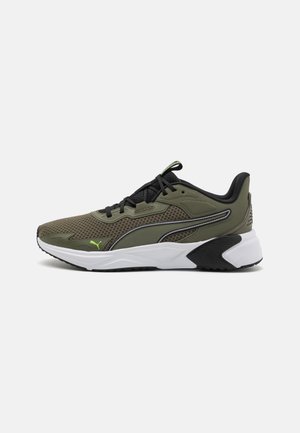 Baskets de sport vert olive et noir en tissu mesh, semelle blanche et lacets noirs, présentées sur un fond gris clair uni.