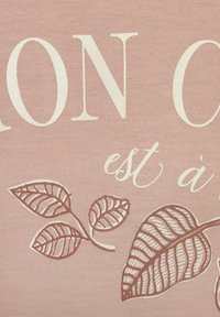 Cotton fabric in soft pink featuring cream text and brown leaf illustrations with detailed veins, creating a textured visual effect.