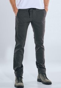 Kohlefarbene Hose aus Gewebestoff, mit einem Kordelzugbund, Seitentaschen, Slim Fit und strukturierter Oberfläche. Kombiniert mit Stiefeln.