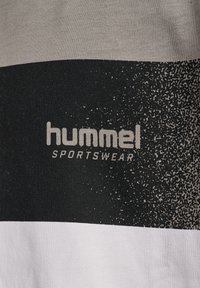 Sort, hvid og grå grafisk T-shirt med teksturerede, horisontale striber, med "hummel SPORTSWEAR"-logo i lysegrå.