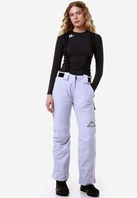 Pantaloni da neve grigi chiari con bretelle nere regolabili, dotati di tasche laterali e un logo sulla gamba inferiore. Tessuto morbido e resistente all'acqua.
