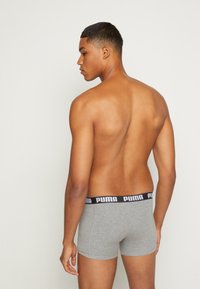 Graue Boxer-Shorts mit einem schwarzen Puma-Bund, von hinten präsentiert, die den glatten Stoff und die enge Passform hervorheben.