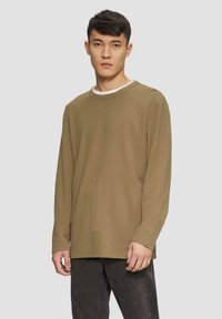 Langärmliges, olivgrünes Hemd aus strukturiertem Material mit Rundhalsausschnitt. Verfügt über einen lässigen Look mit einem weißen Innenkragen.