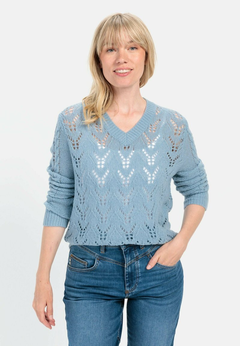Himmelblaues Strickoberteil mit V-Ausschnitt und aufwendigem Spitzenmuster. Hat lange Ärmel und eine lockere Passform, getragen mit Jeans.