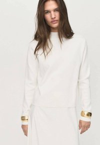 Maglione bianco con scollo rotondo, dotato di maniche lunghe e dettagli dorati ai polsini. Texture morbida, design minimalista.