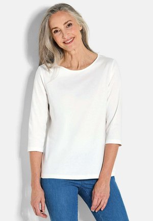 Witte lange mouwen top met een ronde halslijn en driekwartmouwen, gecombineerd met blauwe denim jeans. Gladde textuur, casual ontwerp.