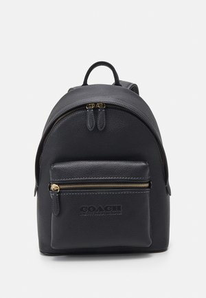 Sac à dos en cuir noir avec poche avant zippée et poignée supérieure, arborant le logo embossé Coach Leatherware.