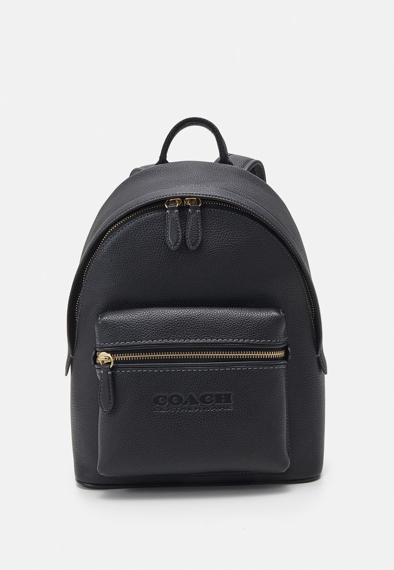 Sac à dos en cuir noir avec poche avant zippée et poignée supérieure, arborant le logo embossé Coach Leatherware.
