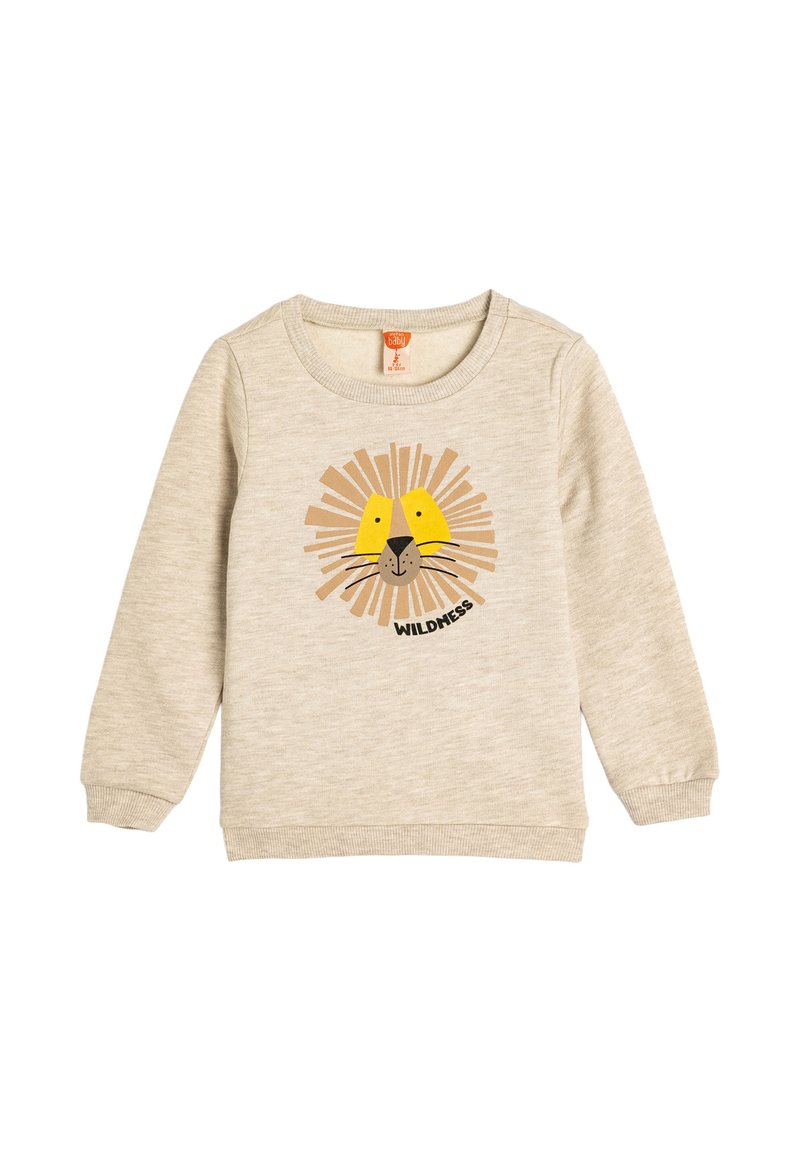 Sudadera de color beige claro hecha de material suave, con un gráfico de cara de león con acentos amarillos y el texto "WILDNESS" debajo.
