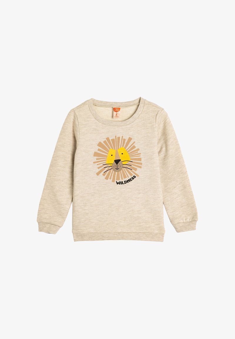 Sudadera de color beige claro hecha de material suave, con un gráfico de cara de león con acentos amarillos y el texto "WILDNESS" debajo.