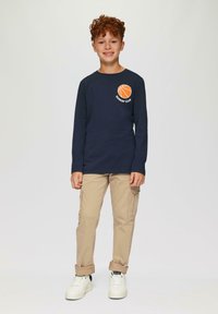 Long-sleeve navy shirt featuring an orange basketball graphic with "DUNKIN' CLUB," paired with beige cargo pants and white sneakers.