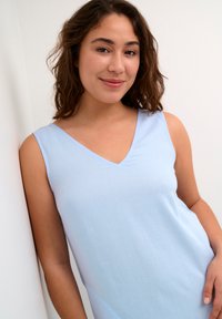 Helleblaue ärmellose Bluse mit V-Ausschnitt, aus glattem Stoff gefertigt, mit lockerer Passform und subtiler Struktur.