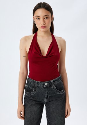 Body a halterneck color bordeaux con scollatura drappeggiata, abbinato a jeans in denim neri a vita alta con tasche frontali e leggera scoloritura.