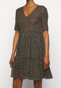 Kukkakuosiset mekko V-aukolla, lyhyillä hihoilla ja kerroksella kootulla hameella. Väriteemana musta, oranssi ja teal-kuviot.