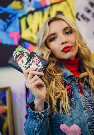 Black wallet featuring a colorful graphic design, depicting a face with vibrant accents. Clasp closure and textured surface.
