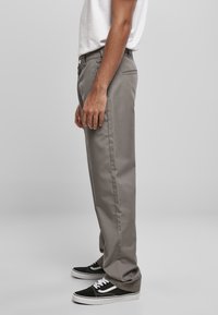 Gray cotton fabric pants with a straight-leg design, featuring side pockets and a button closure, paired with black and white sneakers.