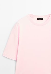 Rosa Baumwoll-T-Shirt mit kurzen Ärmeln, einem runden Ausschnitt und einem kleinen schwarzen Etikett am Kragen. Glatte Textur mit lässiger Passform.