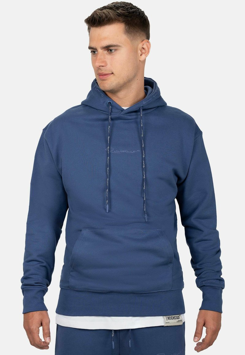 Felpa blu con tasca frontale, cordini regolabili, polsini e orlo a coste. Presenta un branding sottile ricamato sul davanti.