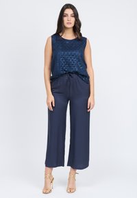Top senza maniche blu navy con un motivo geometrico testurizzato, abbinato a pantaloni larghi blu navy realizzati in tessuto morbido e dotati di una vita con cordoncino.